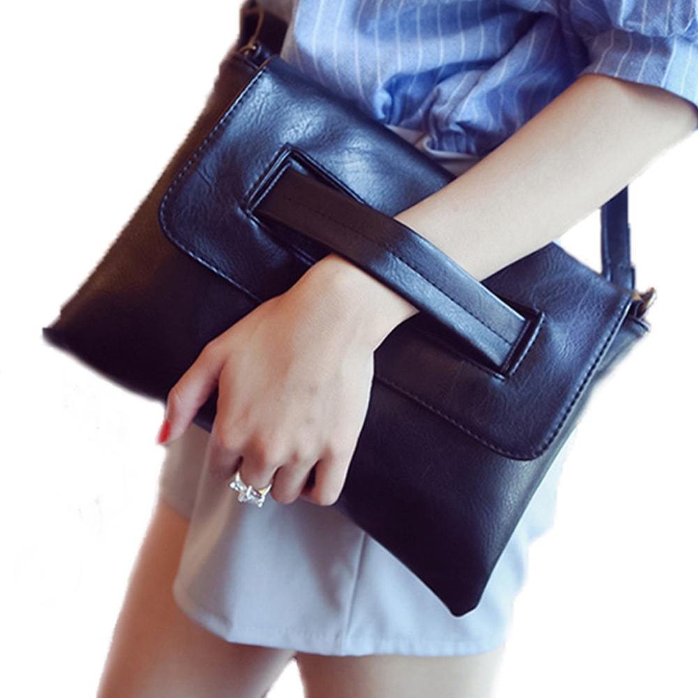 A person holding a sleek, minimalist Black Vegan Leather Envelope Clutch Bag with an attached wrist strap, perfect for a chic and versatile accessory.