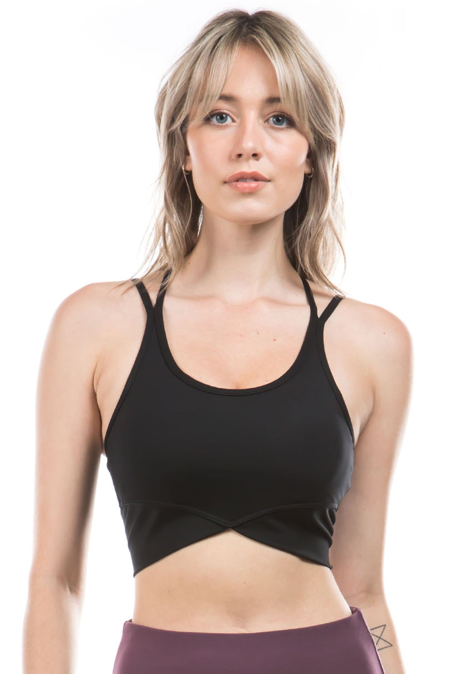 Front view of a woman wearing a black criss-cross sports bra with thin straps and a stylish cut-out design just below the bust. The bra provides medium support, perfect for low to moderate impact activities like yoga or gym workouts.