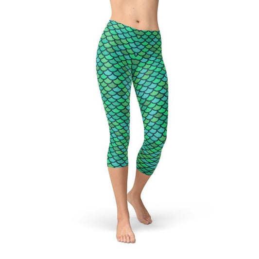 A pair of Green Mermaid Capri Leggings featuring an all-over mermaid scale print in vibrant shades of green and blue. These mid-rise, cropped leggings hug the body, offering a flattering and playful fit, perfect for yoga, workouts, or casual wear.