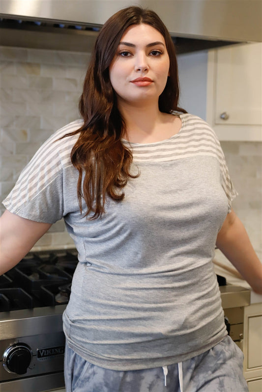 A woman wearing a Grey Stripe Short Sleeve Top made of soft rayon and spandex, featuring a comfortable, relaxed fit. The top showcases horizontal stripes across the shoulders and sleeves, contrasting with the solid grey body, creating a casual yet stylish look.